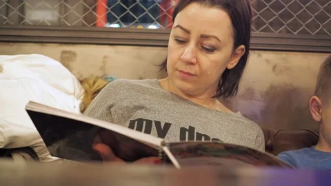 A woman flips through the menu while sitting at a table in a cafe. warm light. a Stock Footage 169358700