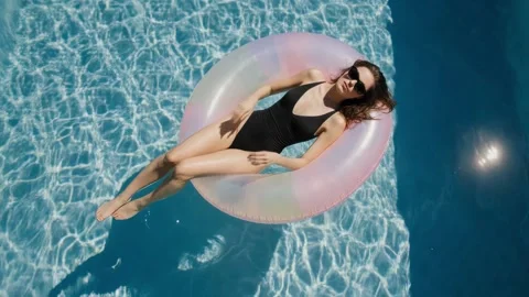 Woman Floating on Inflatable Pool Ring in Black Swimsuit Stock Footage 339104660