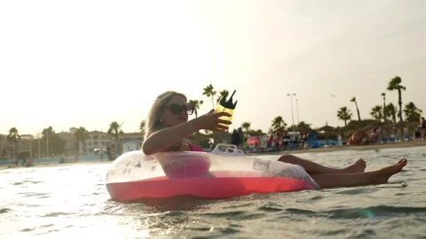 Woman floating on inflatable ring enjoying summer vacation cocktail Stock Footage 337884674