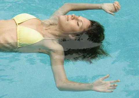 Woman floating in pool Stock Photos