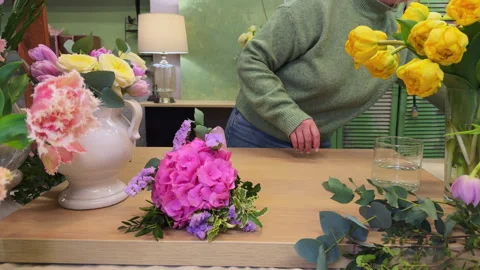 Woman florist assembles a small hydrangea bouquet and makes a colorful package,  Stock Footage 307087228
