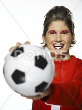 Woman football fan with Swiss flag painted on face, holding football Stock Photos