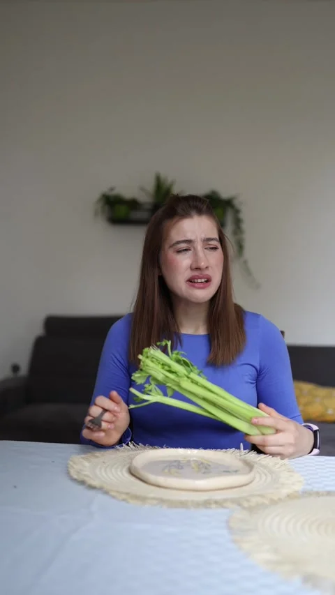 Woman forces herself to choose celery Stock Footage 339854834