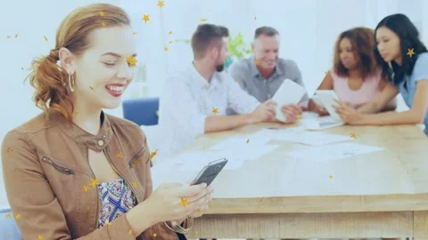 Woman in foreground tapping phone, checking work app and causing gold stars, Stock Footage 334352019