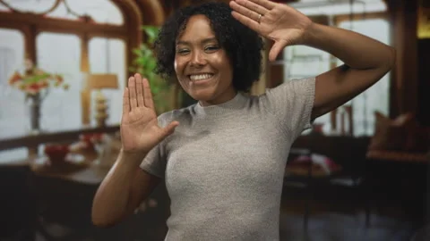 Woman frames her face with hands and smiles in a living room building bathe.. Stock Footage 315526500