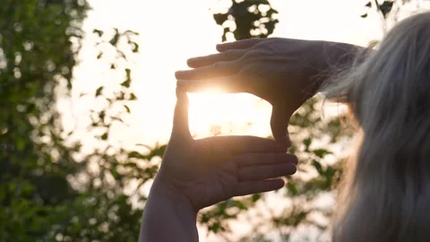 Woman framing setting sun with hands Stock Footage 312740357
