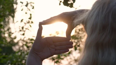 Woman framing setting sun with hands at summer evening Stock Footage 315976008