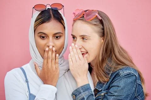 Woman, friends and gossip in shock for secret whisper in ears against pink Stock Photos