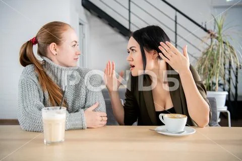 Woman friends sit and feel upset in the restaurant Stock Photos