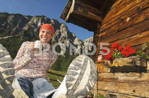 Woman in front of alpine hut, holding mug Stock Photos