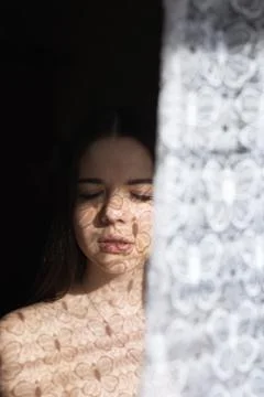 Woman in front of window. The first rays of the sun. Shade from the curtains Foto stock