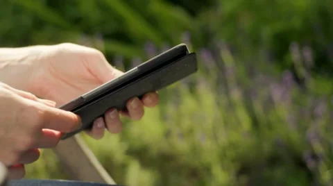 Woman in garden reading on e-reader Stock Footage 11251089