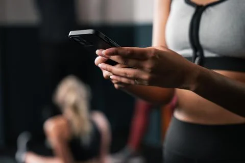 A woman gesturing with her hand using a communication device in the gym Stock Illustration