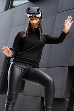 Woman Gesturing Using Virtual Reality Glasses In Metaverse Concept Stock Photos