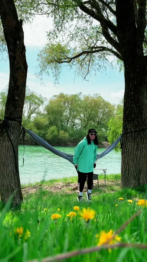 Woman get hammock between trees at blue water river beach Stock Footage 242477478