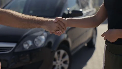 Woman gets the car key from seller - satisfied new car in the background Stock Footage