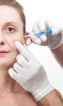 Woman getting botox injection to remove eye wrinkles Stock Photos