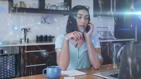 Woman getting call for remote work, taking notes on laptop while tech overlay Stock Footage 333155097