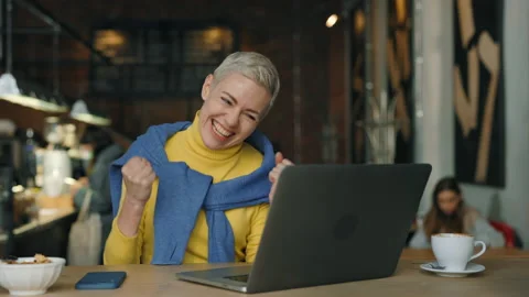 Woman getting good news while working on laptop at cafe Stock Footage 239453189