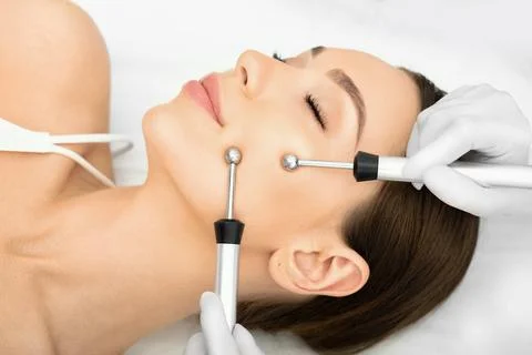 Woman getting microcurrent procedure facelift. Beautician doing anti-aging, t Stock Photos