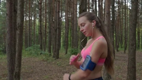 Woman getting ready to run puts on headphones and turns on music on smartphone Stock-Footage 79177641