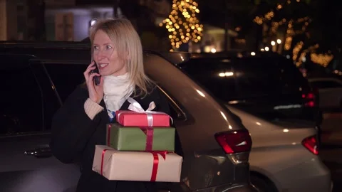 Woman with gift boxes talking on smartphone Night City Stock Footage 280269331