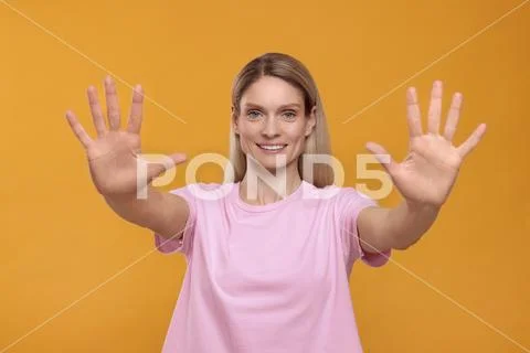 Woman giving high five with both hands on orange background Stock Image ...