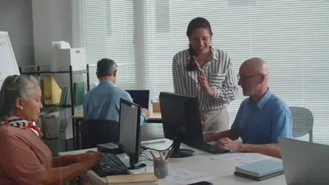 Woman Giving Instructions on Computer Usage to Senior Man during Group Class Stock Footage 263698600