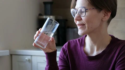 Woman in glasses drinking water in the kitchen, close up Stock Footage 171622853