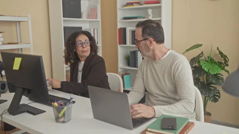 Woman with glasses points to document while man holds smartphone and gestur.. Stock Footage 337413224