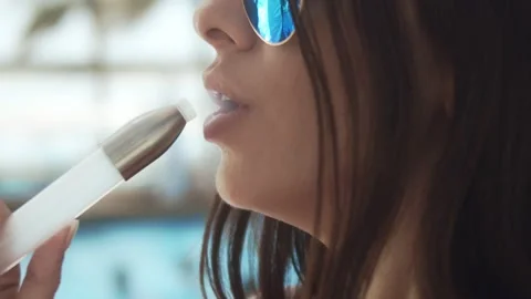 Woman in glasses smokes a hookah while sitting near the pool on a hot summer day Stock Footage 200811414