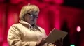 Woman with glasses stands near the red building and uses Tablet PC HD Footage
