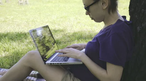 Woman in glasses using laptop computer in the park. 스톡 동영상 50542373
