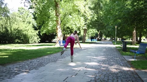 Woman glides on one inline skate practicing balance and control in a park Видео 342267718