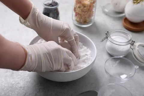 Woman in gloves making bath bomb mixture at grey table, closeup Stock Photos