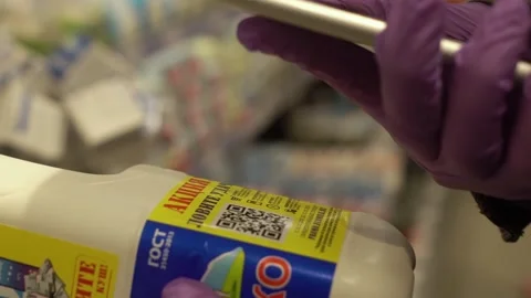 A woman in gloves scans the QR code on a check on a milk box from a supermarket. Stock Footage 131479115