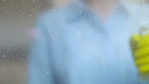 Woman in gloves spraying cleaning detergent on window and mopping it, closeup Stock Footage