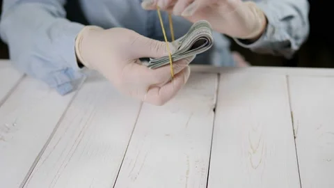 A woman in gloves ties a stack of dollar bills with a rubber band for money. Stock Footage 168162406