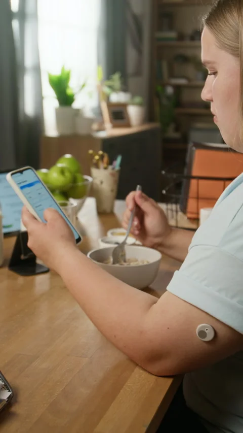 Woman with Glucose Sensor Checking App on Smartphone at Breakfast Stock Footage 346290950