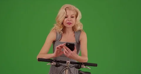 Woman going on bike ride using cell phone for directions on green screen Stock Footage
