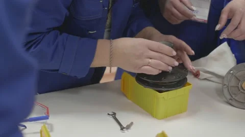 The woman gradually reassembles the part from the components under the guidance Stock Footage 147254627