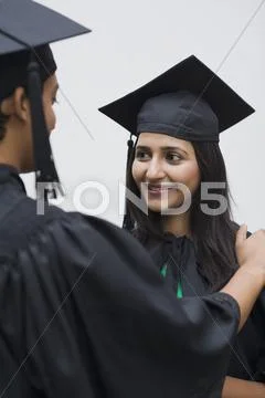 Woman in graduation gown smiling at her friend Stock Photos