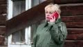 Woman in green raincoat stands near uninhabited house and talks on cell phone HD Footage