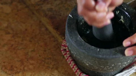Woman Grinding Garlic In A Mortar And Pestle While Cooking Stock Footage