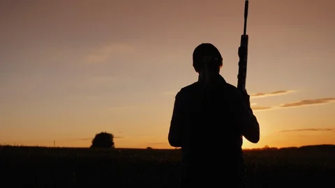 A woman with a gun goes across the field. The beginning of the hunting season Stock Footage
