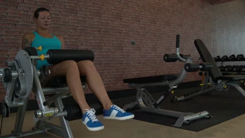 A woman is in the gym. Performs an exercise machine for leg extension Stock Footage 92264811