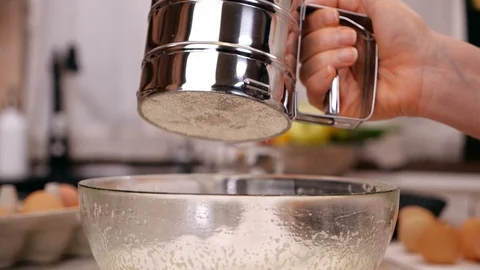 Woman hand adding flour to cake ingredients in glass bowl - slow motion 動画素材 101863393