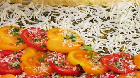 Woman hand adding fresh red and yellow tomato slices onto cottage cheese dough.  库存影片 342283438