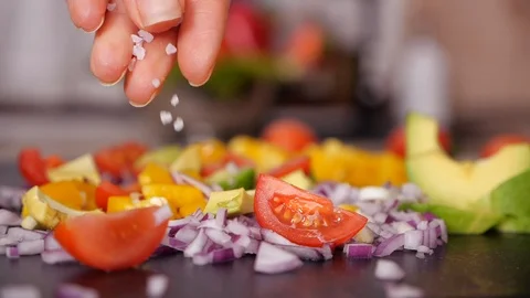 Woman hand adding large grain salt to vegetables mix  - slow motion Video stock 105292642