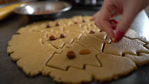 Woman hand adding nuts to raw cookies cut in form of christmas tree closeup Stock Footage 100092466
